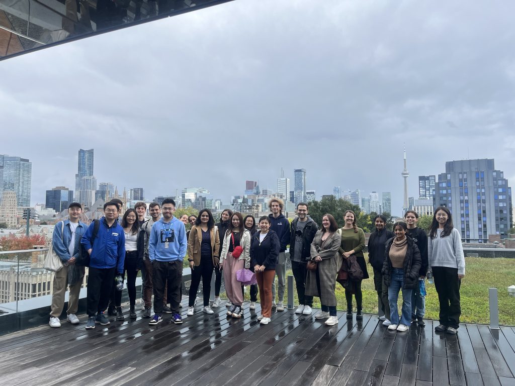 A group of students standing and smiling on a rooftop patio on campus.