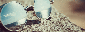 Sunglasses on a beach reflecting the ocean