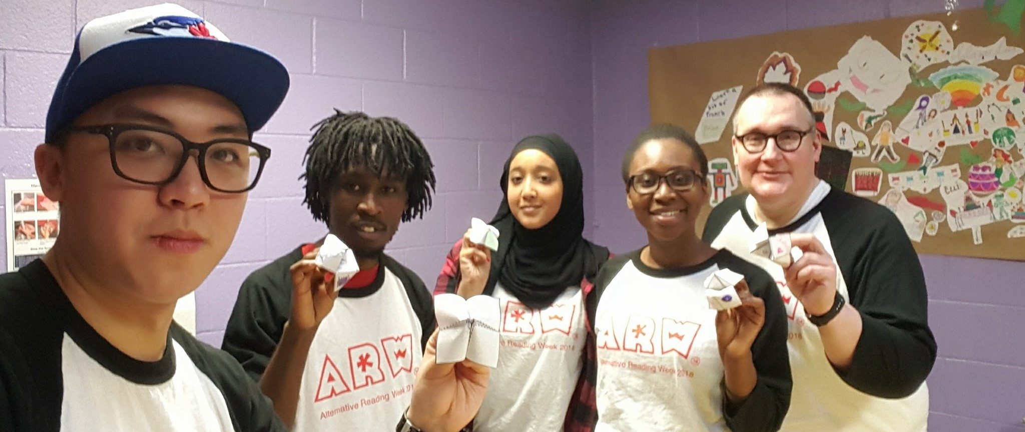 Five Alternative Reading Week participants from 2018 smiling and holding up origami fortune tellers.