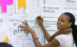 Young woman posting a paper on notice board