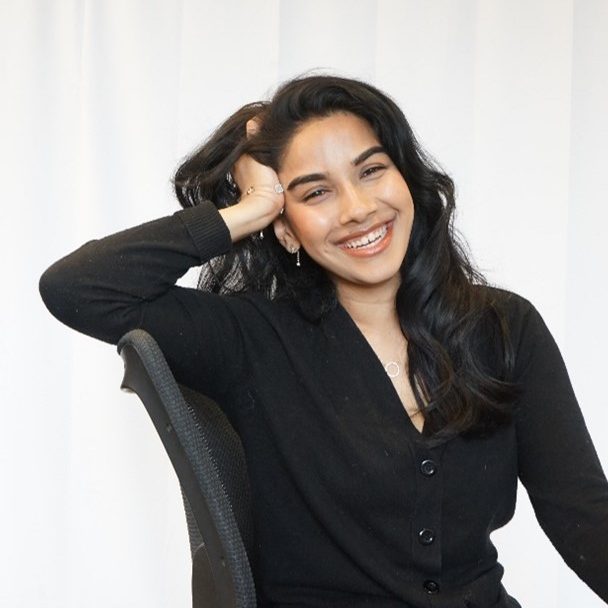 Afshana leaning back against a chair and smiling.