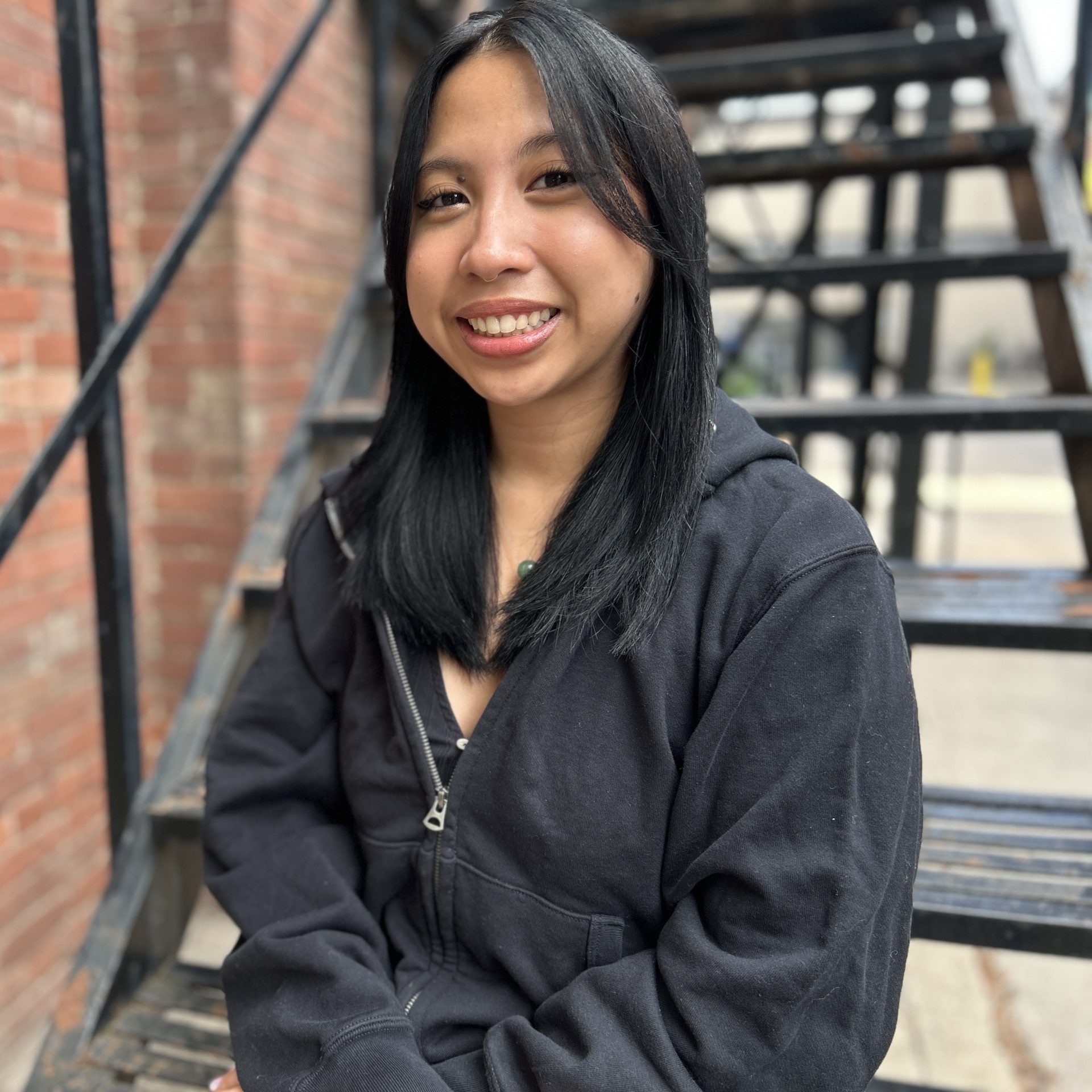 Headshot of Catherine smiling and sitting on a staircase.