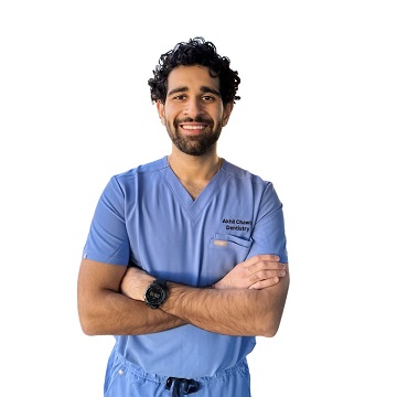 Akhil wearing scrubs and standing with his arms crossed and smiling.
