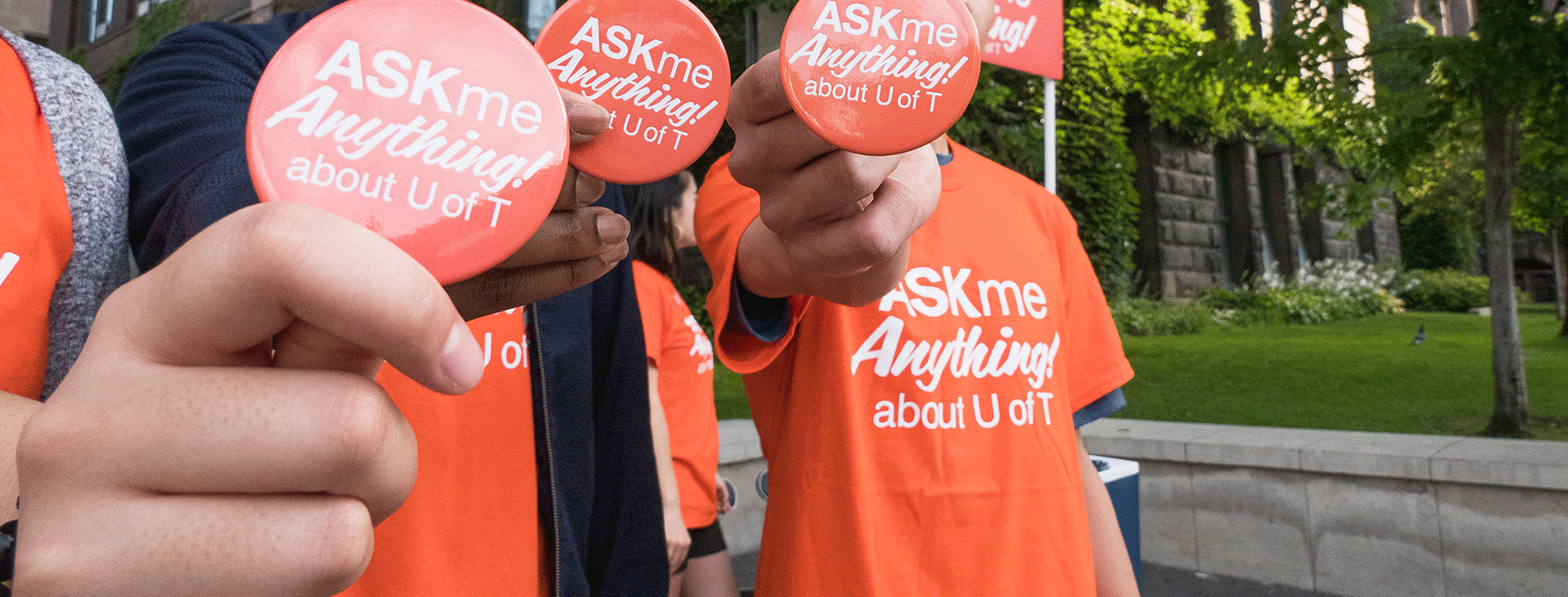 Three students holding up buttons to the camera that say Ask Me Anything about U of T.