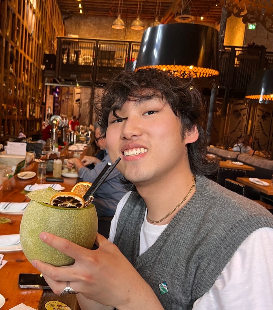 Edwin smiling and holding a drink in a restaurant.