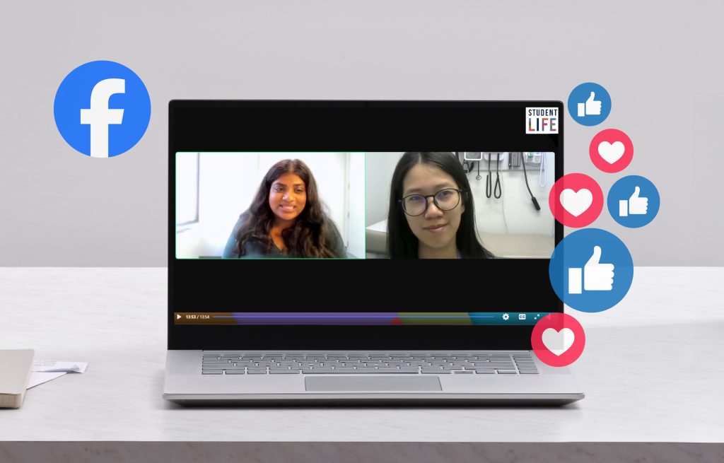 An open laptop on a desk. The screen is showing a facebook live interface with a side-by-side view of two people talking. Graphics of the facebook logo and facebook heart and like icons surround the screen.