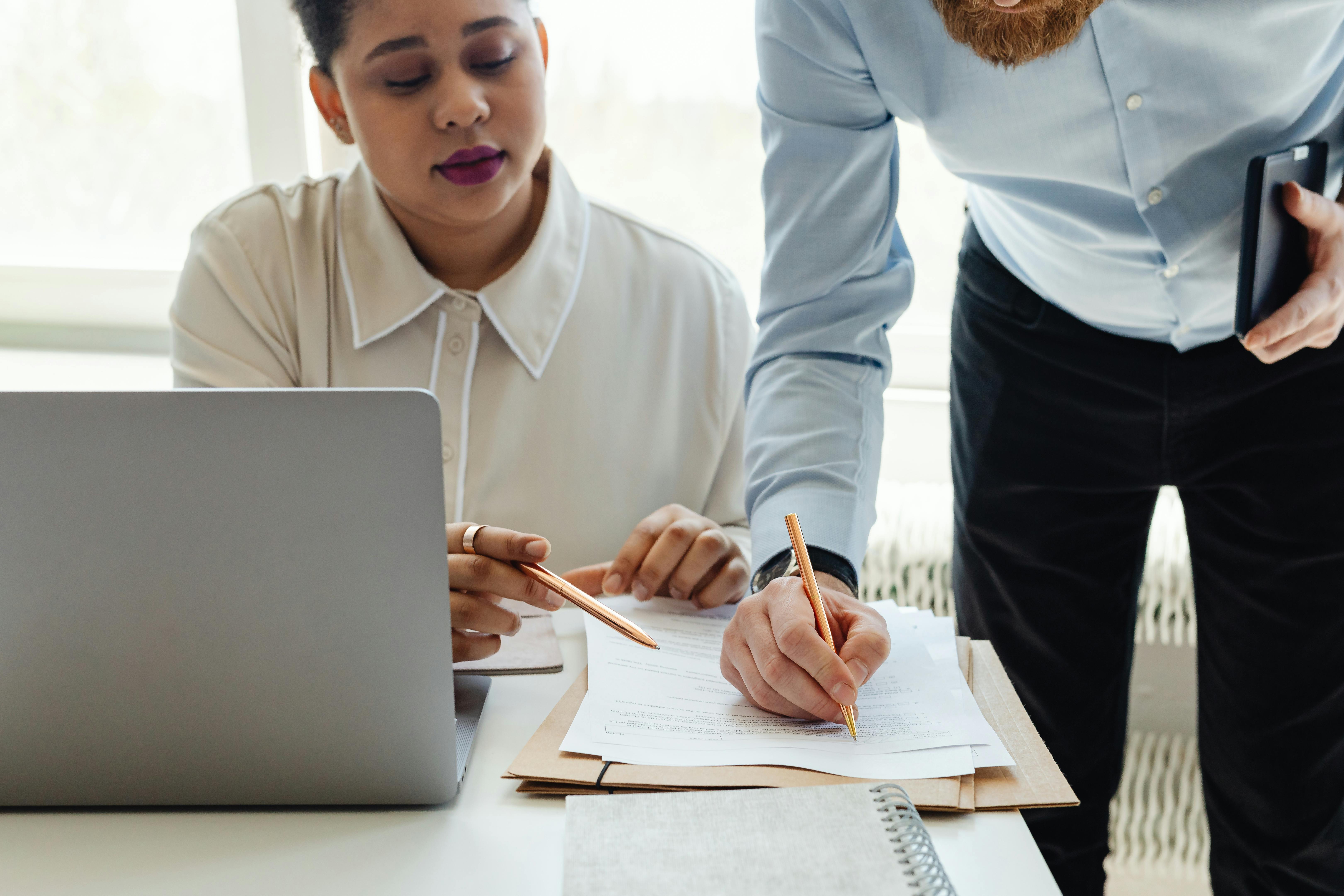 Two people at a desk, looking over a document together.