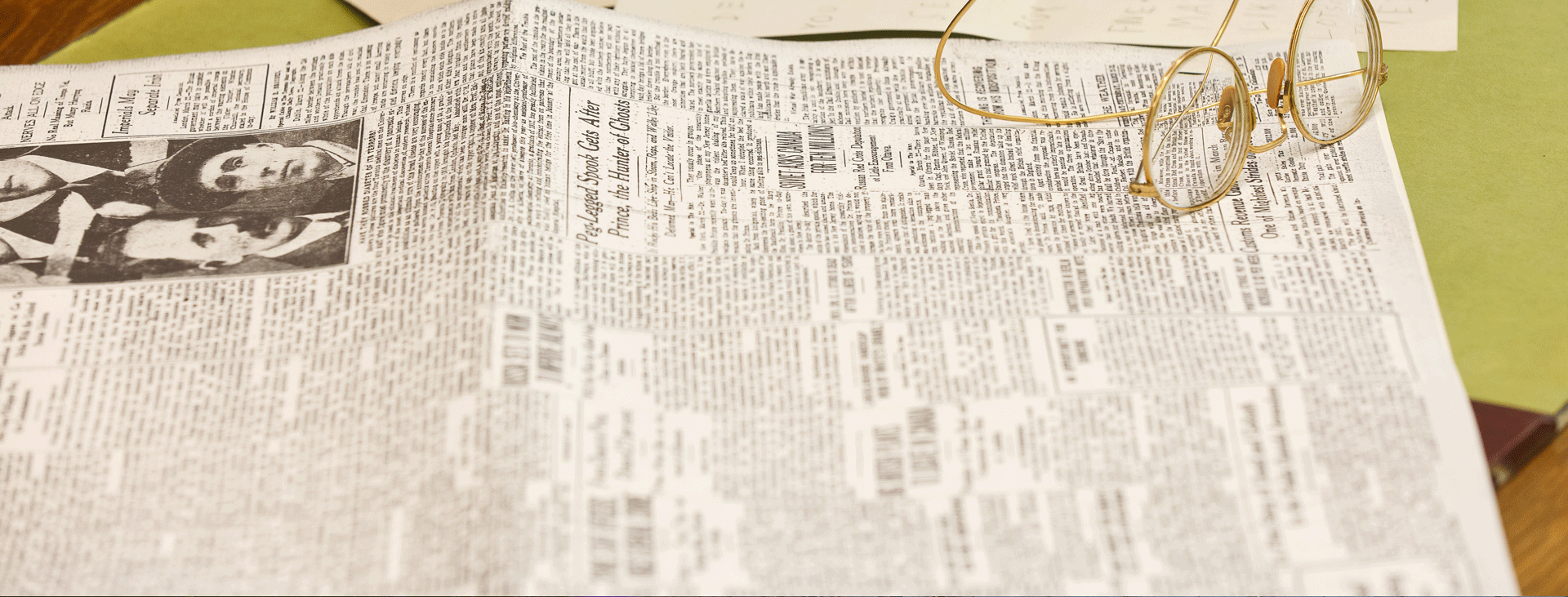 A pair of glasses sitting on an old newspaper