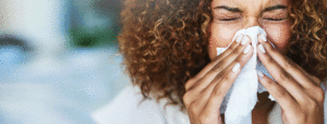 Young woman with curly hair blowing her nose
