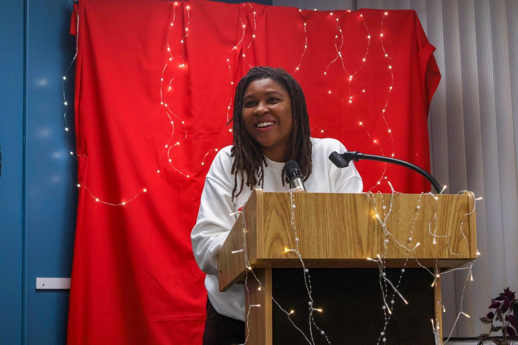 A student standing behind the podium, looking out at the crowd and smiling as they perform their piece.