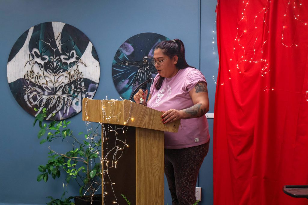 A student holding the microphone and resting their other hand on the side of podium as they perform their piece.