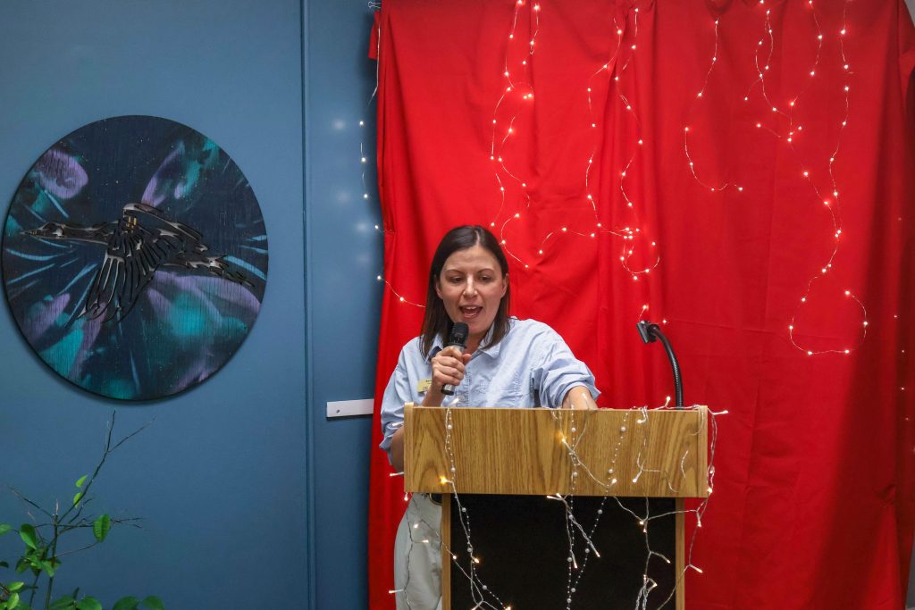 A staff member from Accessibility Services holding a microphone and speaking behind the podium.