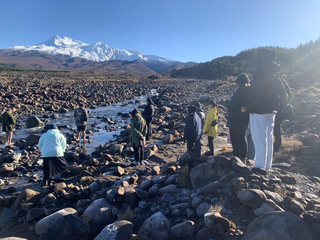 Group of students standing on rocks around ’Koro’ (grandfather) Ruapehu Mountain.