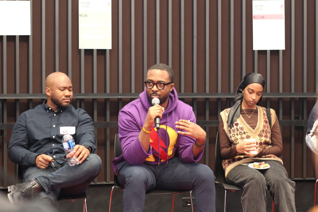 3 people sitting and listening while one person speaks into a mic.