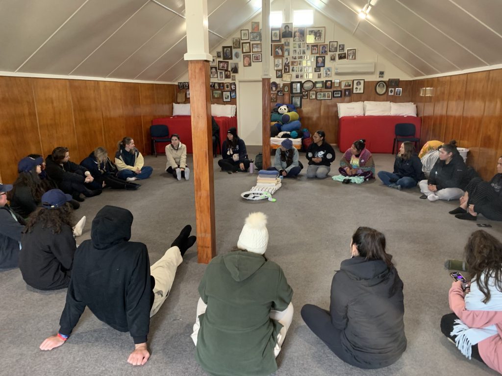 Students sitting in a circle inside the Marae.