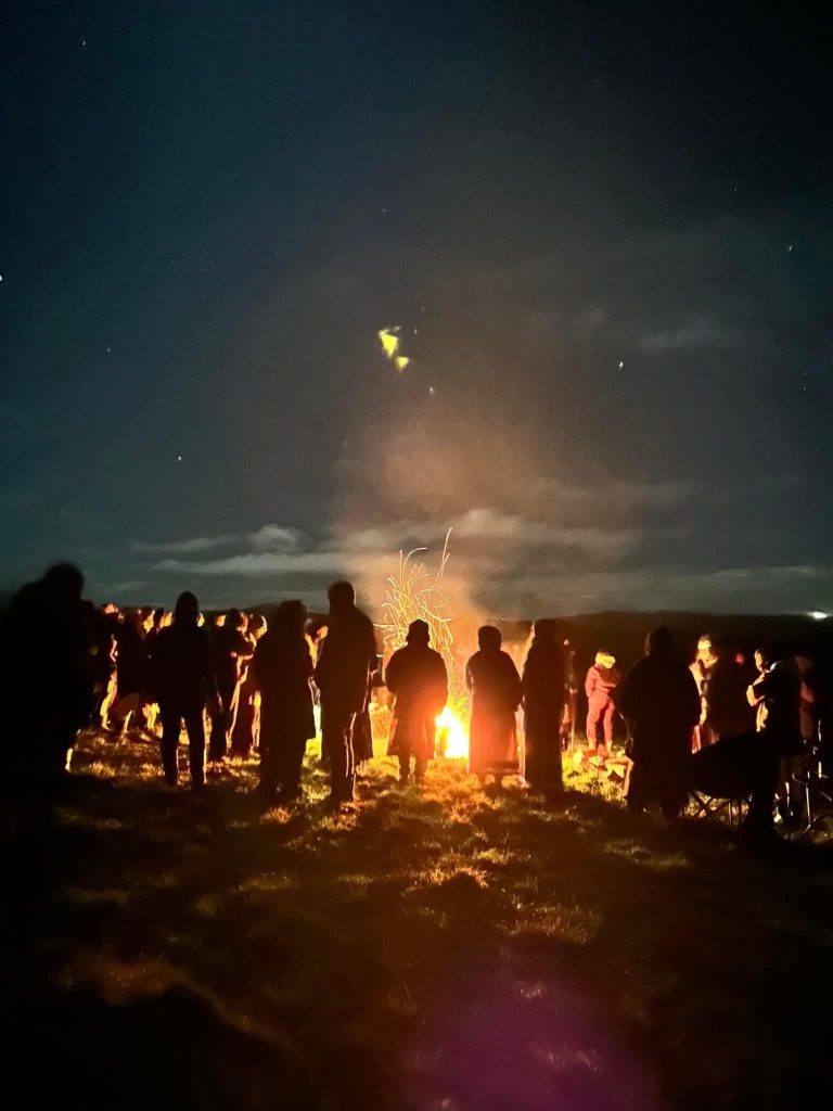 Students gathered around a fire in the early morning before sunrise.