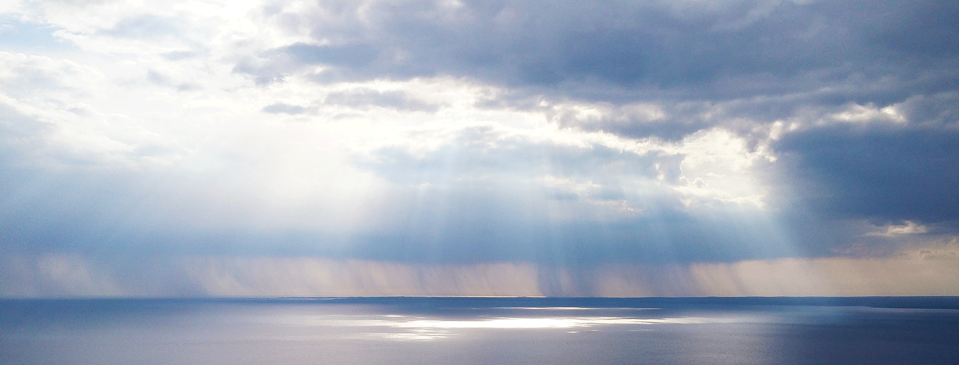 Cloudy sky with light streaming through to touch water
