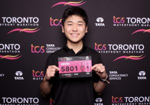 Kevin smiling and holding a Toronto Waterfront Marathon ticket.