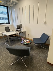 Two chairs facing each other with a coffee table of resources in between inside Student Commons, Room 246.