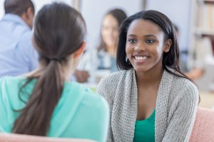 Black student smiling at peer wearing turquoise