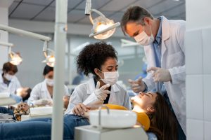Teacher supervising a student examining a patient at dental school