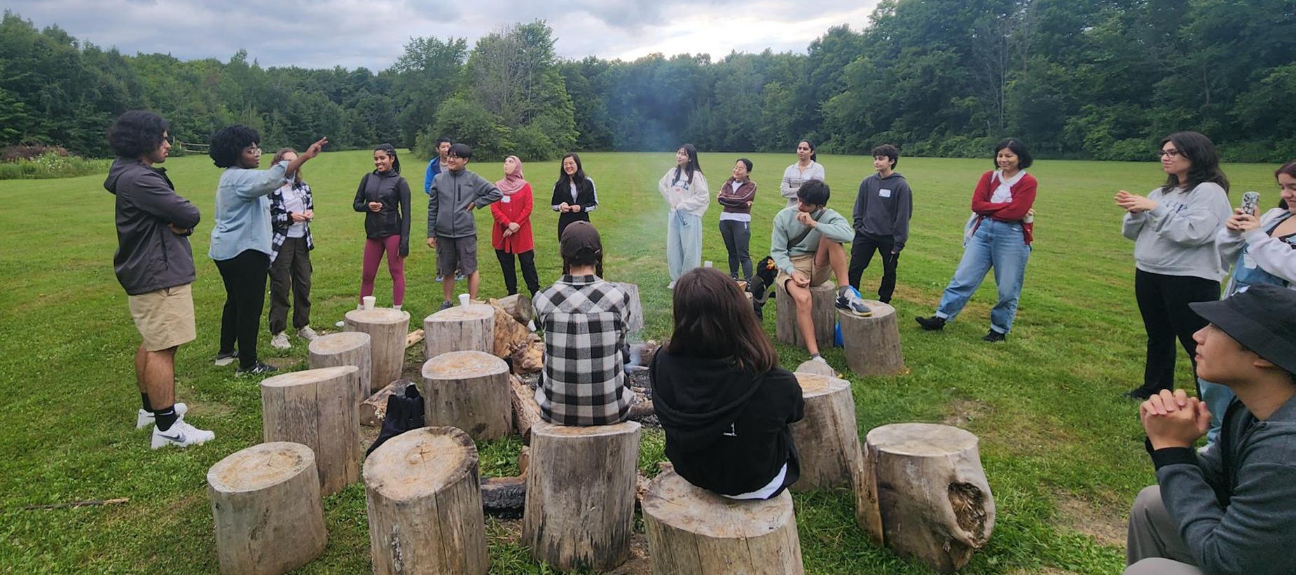 people standing and sitting around a campfire during the day