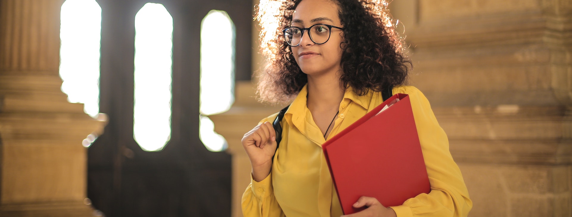 Young woman wearing glasses carrying red binder